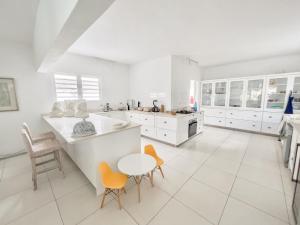 康隆尼角Villa White Horizon by Sealodge的白色的厨房配有白色橱柜和橙色椅子