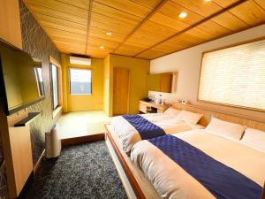 福冈NK Hotels的一间卧室配有两张床和电视。