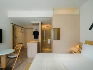 大阪Zentis Osaka的一间卧室配有一张床铺和一张桌子,还设有一间厨房