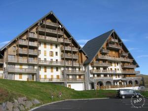 贝斯和圣阿纳斯泰斯Appartement Hauteurs Super Besse - 4 personnes -Piscine & Garage的一座大型公寓楼,前面设有停车场