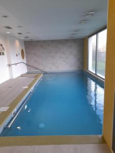 新城勒鲁瓦多米蒂斯莱沙布勒多洛公寓式酒店的蓝色海水大型室内游泳池