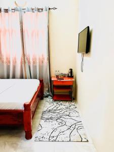 MaziziniNakupenda的一间卧室配有一张床和一张桌子及电视