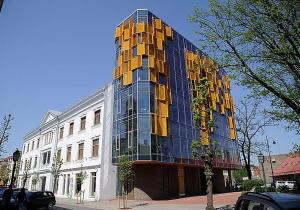 采西斯Cēsu apartamenti的街上一座高大的玻璃建筑,有黄色的窗户