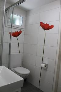 图恩NEB-THUN Studio am Thunersee的浴室设有卫生间,墙上挂着红色鲜花。