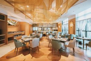曼谷SILQ Hotel & Residence, Managed by The Ascott Limited的一间带桌椅和大型天花板的餐厅