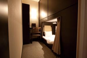 福冈HEARTS Capsule Hotel & Spa Nakasu -Male only-的小房间设有一张床和一张书桌