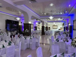 弗尔蒂切尼Hotel Turist的宴会厅配有白色桌椅和紫色照明