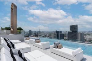 曼谷 曼谷素坤逸怡思得酒店的一个带白色家具的屋顶游泳池和一个游泳池