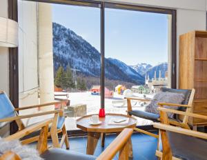 伊索拉2000SOWELL HOTELS Le Pas du Loup的阳台配有桌椅和大窗户。