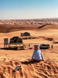 ShāhiqOman desert private camp的坐在沙漠沙子里的人