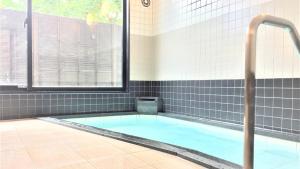 MurayamaMurayama Nishiguchi Hotel的带窗户和热水浴池的浴室