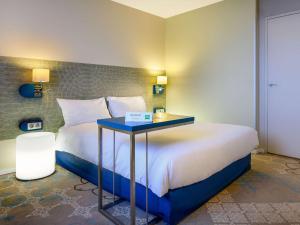 图尔风格旅游中心宜必思酒店的酒店客房,配有一张带蓝色桌子的床