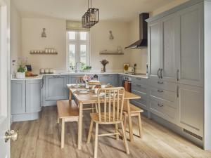 赫特福德Bridge House at Woodhall Estate的厨房配有蓝色橱柜和木桌及椅子