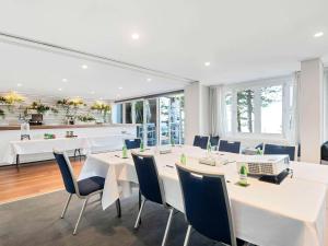 悉尼Peppers Manly Beach的用餐室配有白色的桌子和蓝色的椅子