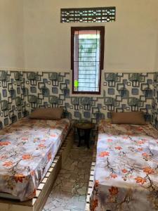 外南梦Ohana Homestay Banyuwangi的两张床位于带窗户的房间内