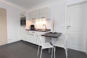TarnewitzBungalow Mariannenweg 4的厨房配有白色橱柜和桌椅