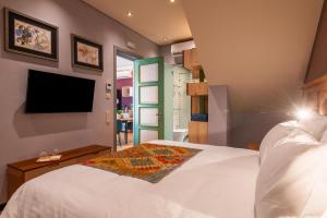 阿尔布费拉Vila Origens Boutique Hotel Albufeira – Adults Only的卧室配有白色的床和平面电视。