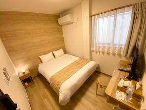 新宫市AJITO Hostel & CafeBar的一间卧室配有一张床、一张书桌和一个窗户。