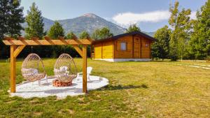 普卢日内Vikendice Gornja Brezna - Mountain cabin Gornja Brezna的田野上的小屋,前面有两把椅子