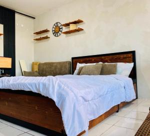 Santa RosaCasa Cabilao Staycation的一间卧室配有一张大床,墙上挂着一个时钟