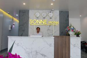 Ðộng HỏiSonne Hotel Quang Binh的坐在酒店接待处的男人