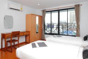 曼谷Double DD House at MRT Sutthisarn的客房设有两张床、一张桌子和一个窗户。