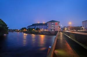 戈尔韦Leonardo Hotel Galway - Formerly Jurys Inn的享有夜间河景,设有一座建筑