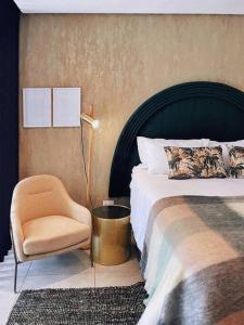 乌姆兰加Dolce vita luxurious apartment的一间卧室配有一张床、一把椅子和一盏灯