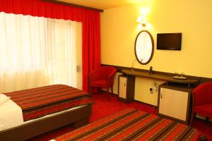 阿马拉达纳酒店的酒店客房带一张床、一张书桌和一面镜子