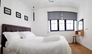 地拉那Tirana Central Apartments - Premium的一间卧室配有一张带白色床单的床和一扇窗户。