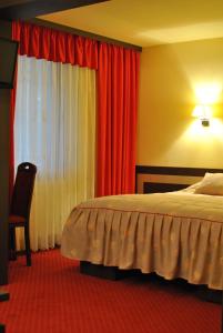 阿马拉达纳酒店的一间卧室配有床和红色窗帘的窗户