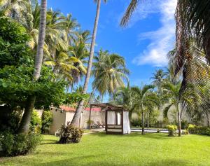 El PorvenirCasa De Playa El Encanto的一座种有棕榈树的花园,一座小建筑