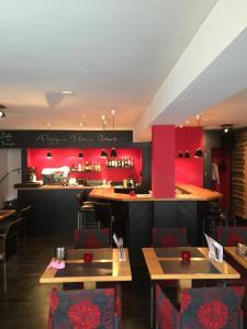 波朗特吕Hôtel-Restaurant Le Lion d'Or的一间设有红色墙壁和桌子的餐厅和一间酒吧