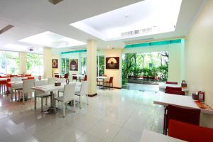 曼谷卡里普佐曼谷酒店的餐厅设有白色的桌椅和窗户。