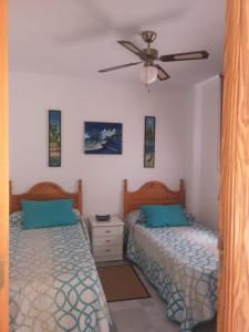 阿尔姆尼卡Casa Gran Tropicana playa a 2 minutos.的一间卧室配有两张床和吊扇