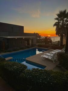 康康Blumen Hotel的一个带2把躺椅的游泳池,享有日落美景