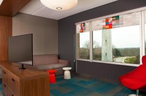 罗利雅乐轩罗利酒店的客厅配有电视、椅子和窗户
