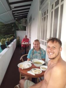 康提Kandy Mountain Cottage的坐在餐桌旁吃饭的男人和女人