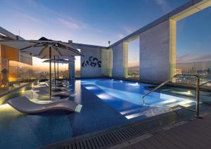 多哈Embassy Suites By Hilton Doha Old Town的一座大楼顶部带遮阳伞的游泳池
