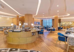 多哈Embassy Suites By Hilton Doha Old Town的一间带桌椅的餐厅和一间酒吧