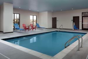 Flower MoundHome2 Suites By Hilton Flower Mound Dallas的游泳池位于酒店客房内,配有蓝色和红色的椅子