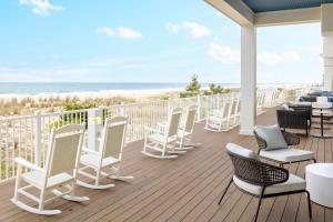 大洋城Hilton Garden Inn Ocean City Oceanfront的配有桌椅的甲板,享有海滩美景