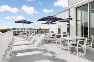 大洋城Hilton Garden Inn Ocean City Oceanfront的庭院里摆放着一排桌椅和遮阳伞