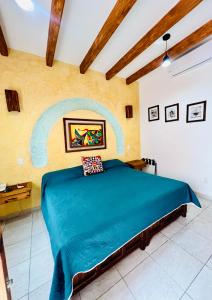 瓦哈卡市Los Arrayanes的卧室配有一张蓝色的床,墙上挂着一幅画