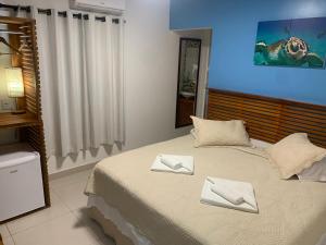 费尔南多 - 迪诺罗尼亚Pousada Flôr do Atlântico的一间卧室配有一张带两条白色毛巾的床