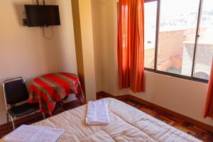 科帕卡巴纳Hostal Sonia的一间卧室设有一张床、一个窗口和一把椅子