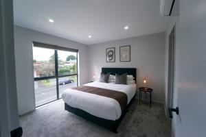 奥克兰Modern Sunnyhills Town House的一间卧室设有一张大床和一个大窗户