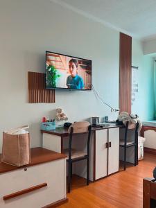 碧瑶Albergo Condotel - AB Pagadian Enterprise的客厅配有书桌和墙上的电视。