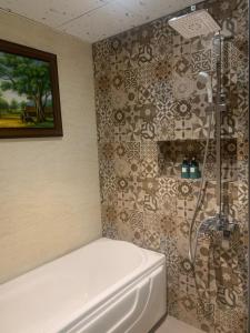 胡志明市Sunflower Luxury Hotel的设有带白色浴缸的淋浴的浴室