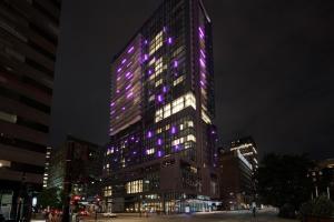蒙特利尔HONEYROSE Hotel, Montreal, a Tribute Portfolio Hotel的一座高大的建筑,上面有紫色的灯